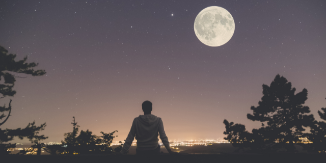 homem observando a lua cheia no céu