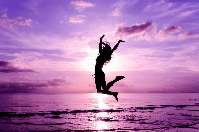 Silhueta de uma mulher pulando enquanto está na praia