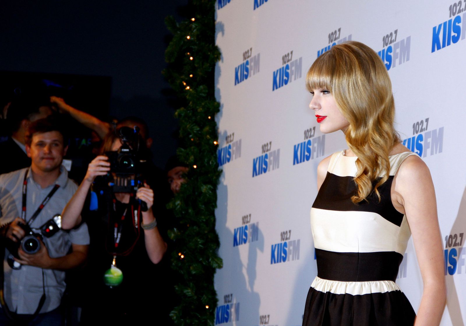 Taylor Swift olhando para frente com fotógrafos ao lado tirando fotos