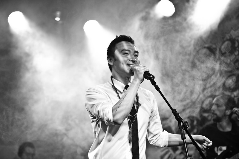 Cantor Dan Nakagawa cantando num microfone.