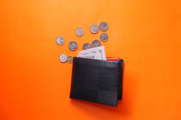 carteira com moedas e notas em um fundo laranja