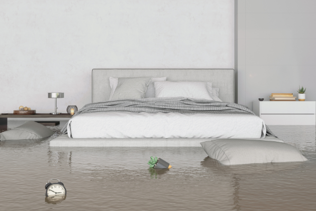 Quarto com uma cama de casal ao meio, inundado.