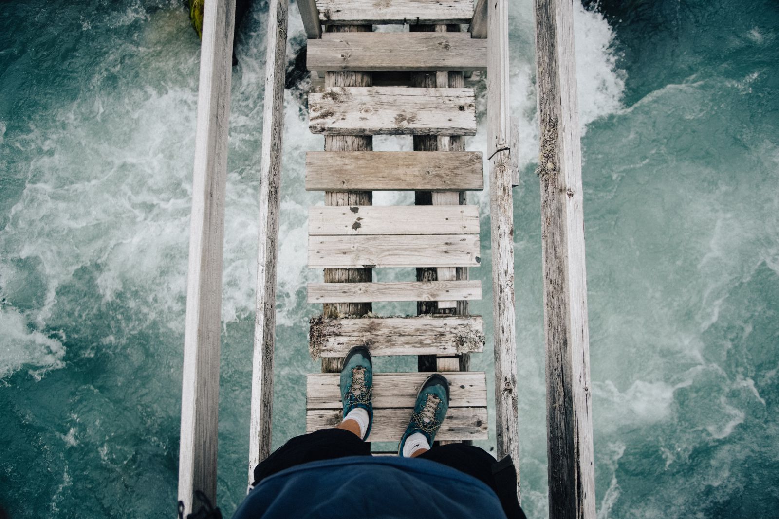 Pessoa em pé em uma ponte com visão para o mar