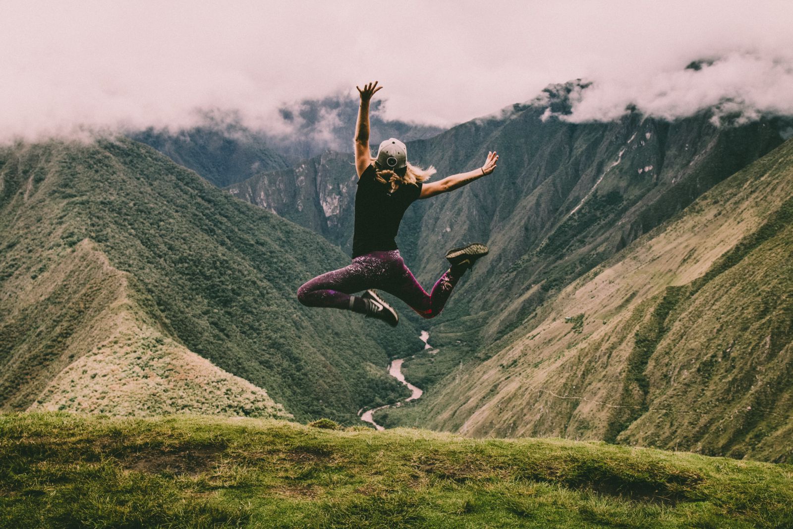Mulher saltando de uma montanha com os braços abertos