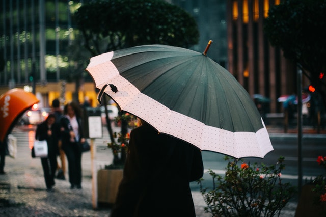 Mulher segurando guarda-chuva na rua.