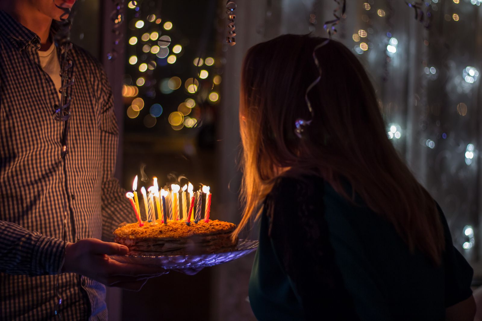 Mulher assoprando as velas de aniversário do seu bolo.