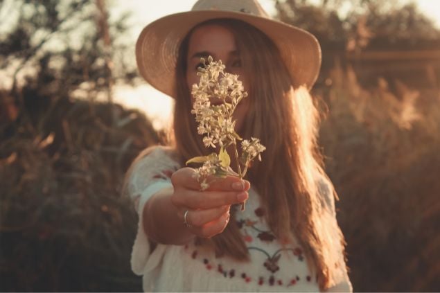 Mulher com chapéu de palha segurando uma flor