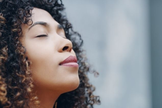 Mulher de olhos fechados respirando fundo