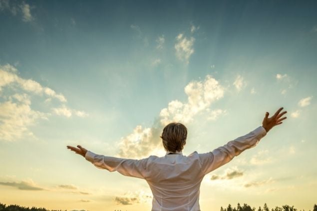 Homem de braços abertos para o céu