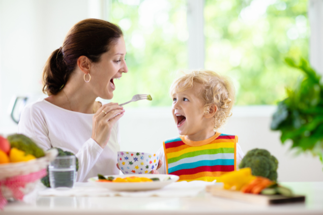 Mãe dando comida na boca do filho