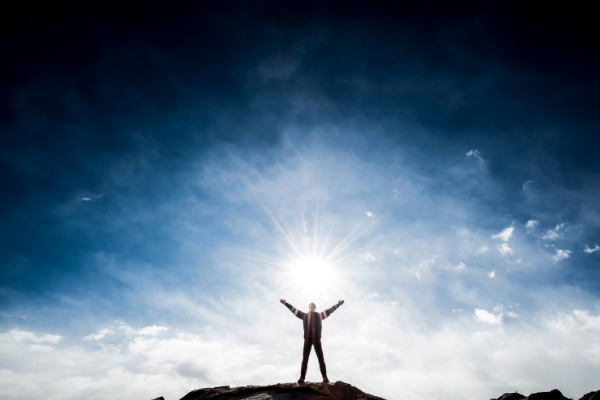 Homem com os braços abertos em direção ao sol