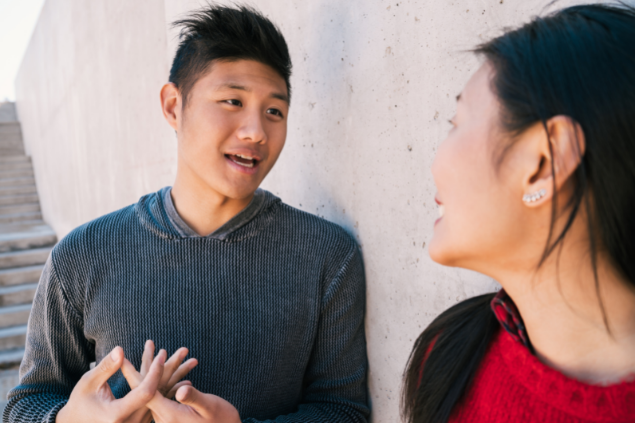 Homem e mulher conversando em frente a um muro