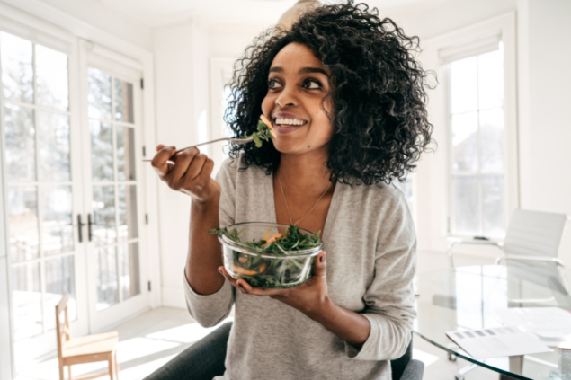 Mulher comendo um bolw com salada