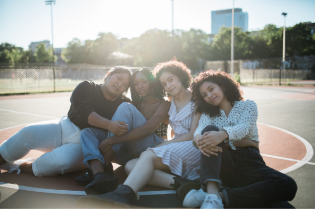 Quatro amigas sentadas em uma quadra de esporte