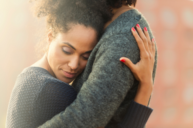 Mulher abraçada em uma outra mulher