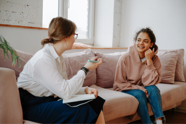 Duas mulheres sentadas no sofá rindo e conversando