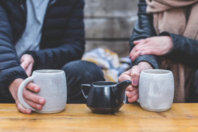 Duas pessoas segurando xícaras de café enquanto conversam