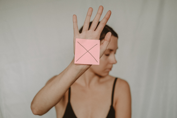 Mulher com um papel à frente da sua mão direita com um xis