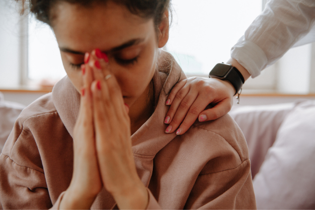 Mulher com olhos fechados e as mãos juntas enquanto ora