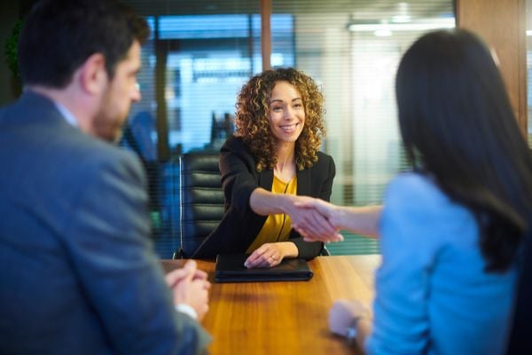 Mulher apertando a mão de outra mulher em uma reunião de negócios