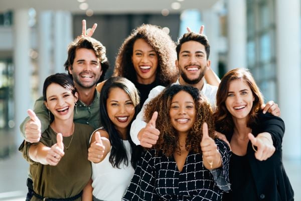 Diversas pessoas sorrindo e fazendo o sinal positivo com as mãos