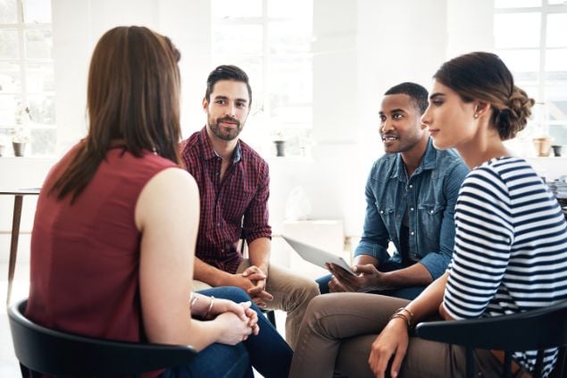 Imagem de um grupo de quatro pessoas conversando em uma roda