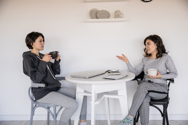 Duas mulheres sentada na mesa da cozinha conversando