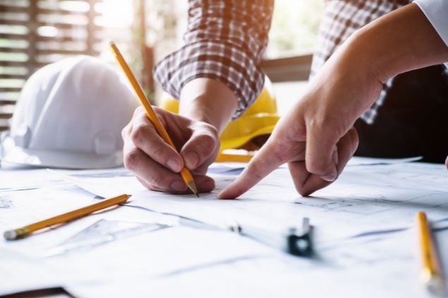 Mãos escrevendo e fazendo projetos em cima da mesa