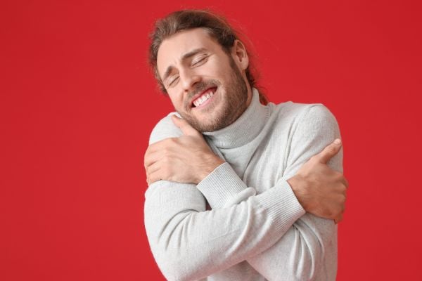 Homem sorrindo e se abraçando