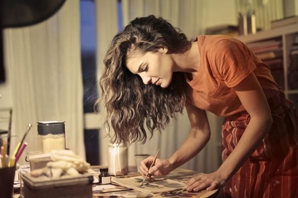 Mulher pintando em uma folha e cima de uma mesa