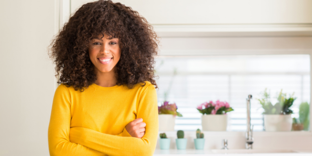 Mulher sorrindo para a foto e de braços cruzados