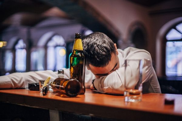 Homem bêbado debruçado no balcão de um bar