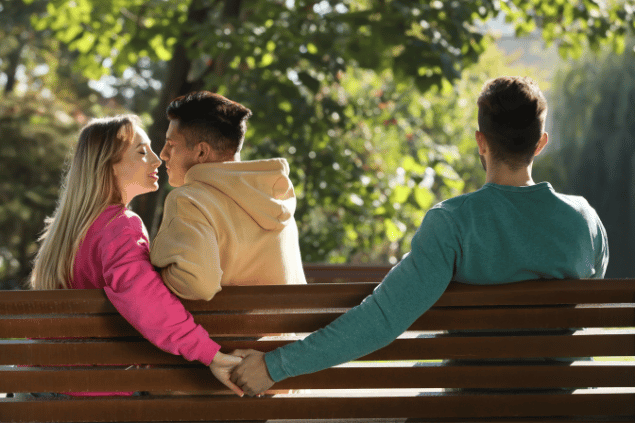 Mulher segurando a mão de outro homem enquanto beija seu namorado. Conceito de triângulo amoroso. 