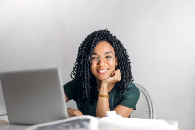 Mulher sorrindo enquanto está sentada em frente a um computador