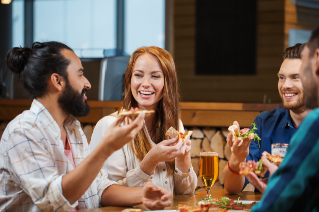 Amigos comendo pizza enquanto conversam e riem