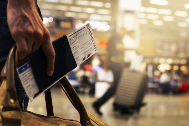 Mão segurando uma passagem área no aeroporto