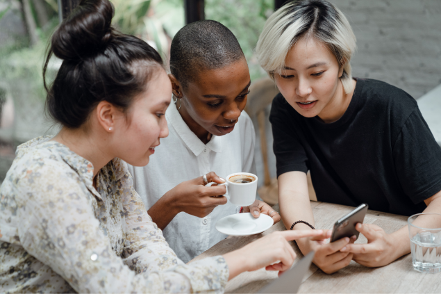 Três mulheres conversando e olhando um celular