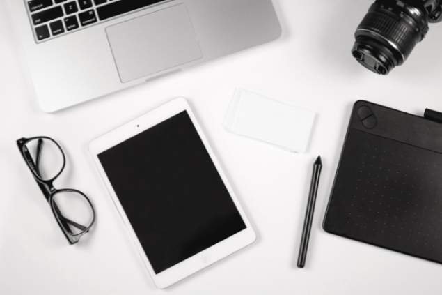 Mesa de trabalho com notebook, tablet e outros acessórios em cima