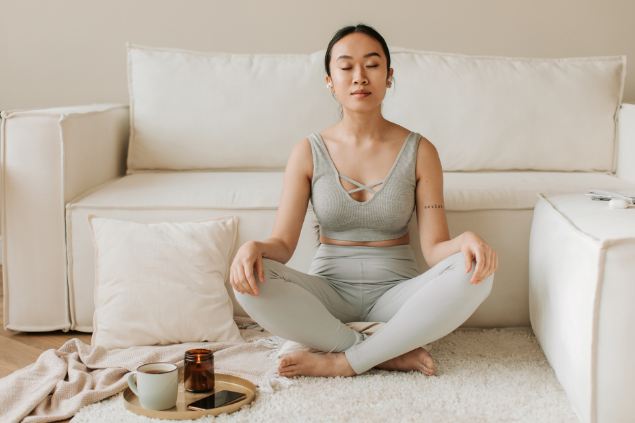 Mulher meditando em sua sala, sentada no tapete 