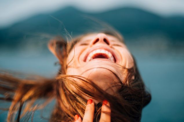 Imagem de fundo azul e em destaque uma mulher feliz e alegria, sorrindo e de bem com a vida.