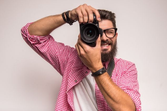 Imagem de um homem fotógrafo segurando um câmera fotográfica.