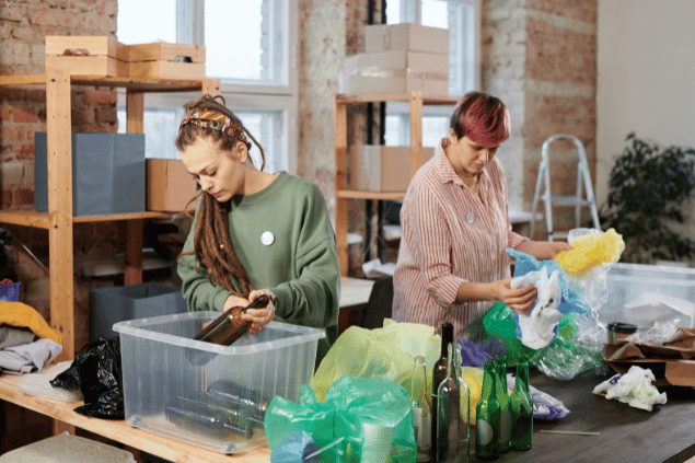 Duas mulheres separam garrafas e lixos para a reciclagem.