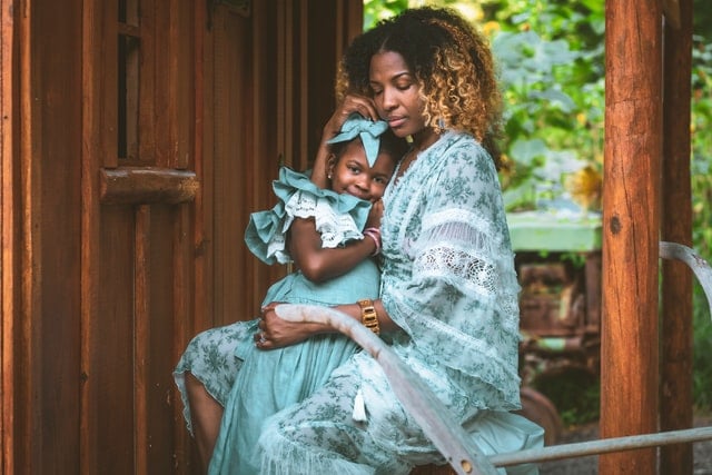 Mulher branca segurando bebê negra no colo.