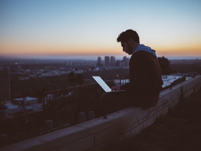 Homem sentado com notebook no colo.