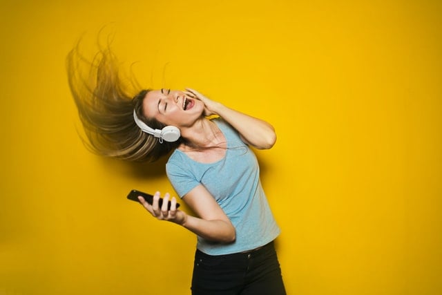 Mulher branca de fones e balançando a cabeça.