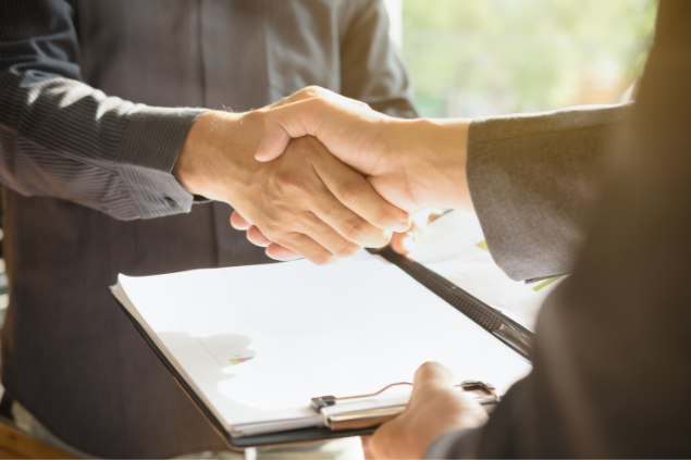 Duas pessoas apertando as mãos, firmando um contrato