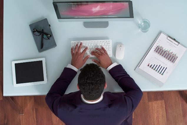 Homem trabalhando organizadamente em seu computador.