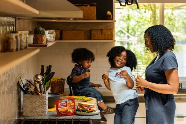 Mulher e crianças numa cozinha.