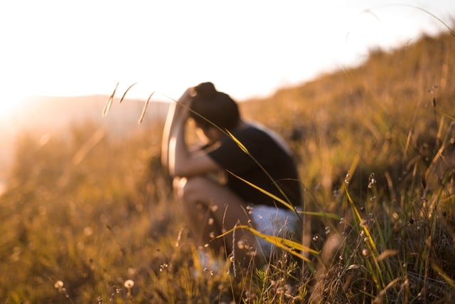 Jovem branca sentada num campo.