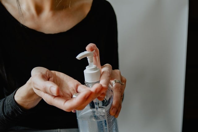 Mulher branca passando álcool em gel.